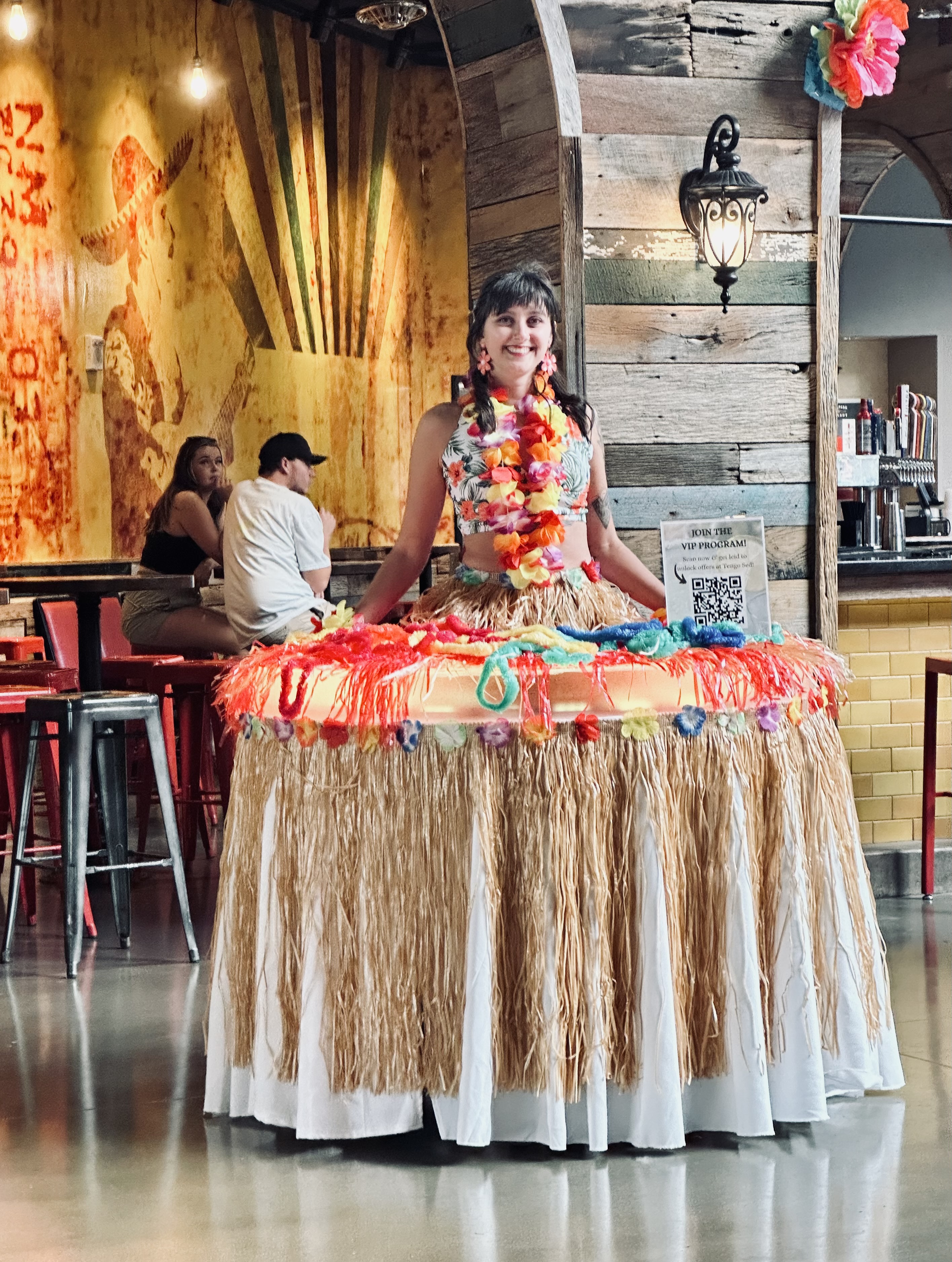 Hawaiian lei table with grass skirt roaming through parties and events